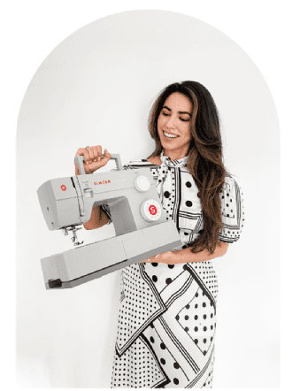 Grazyela Couto, estilista, modelista e costureira, segurando uma máquina de costura